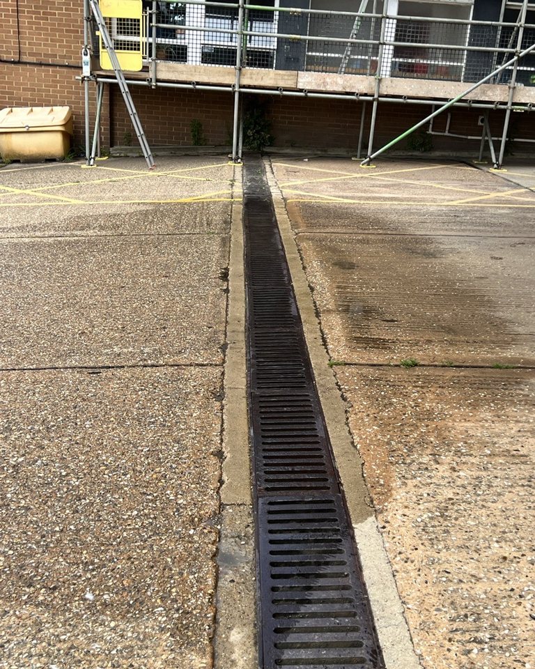 Linear channel drain crossing a paved commercial service area